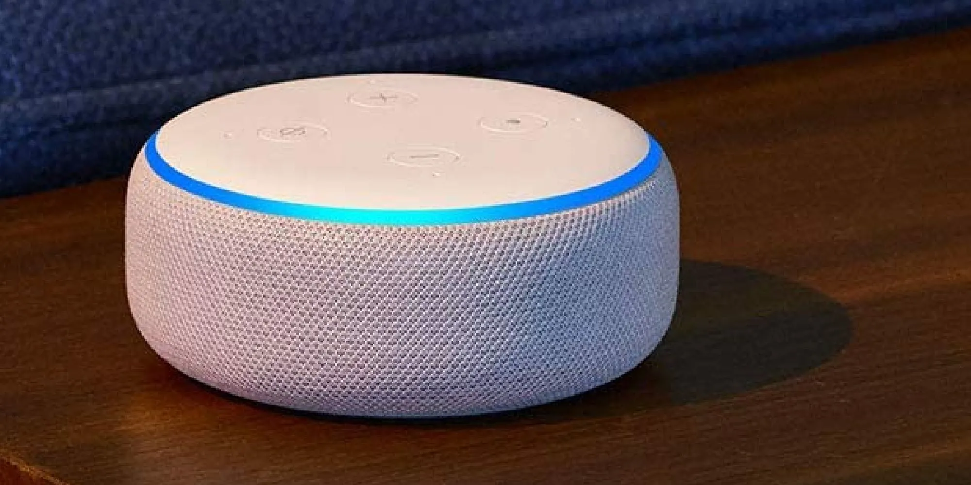 Thiết bị Amazon Alexa màu trắng đặt trên bề mặt gỗ, minh họa cho loa thông minh có thể được biến đổi thành 'Gamer Alexa' với phong cách và giọng điệu đặc trưng game thủ.