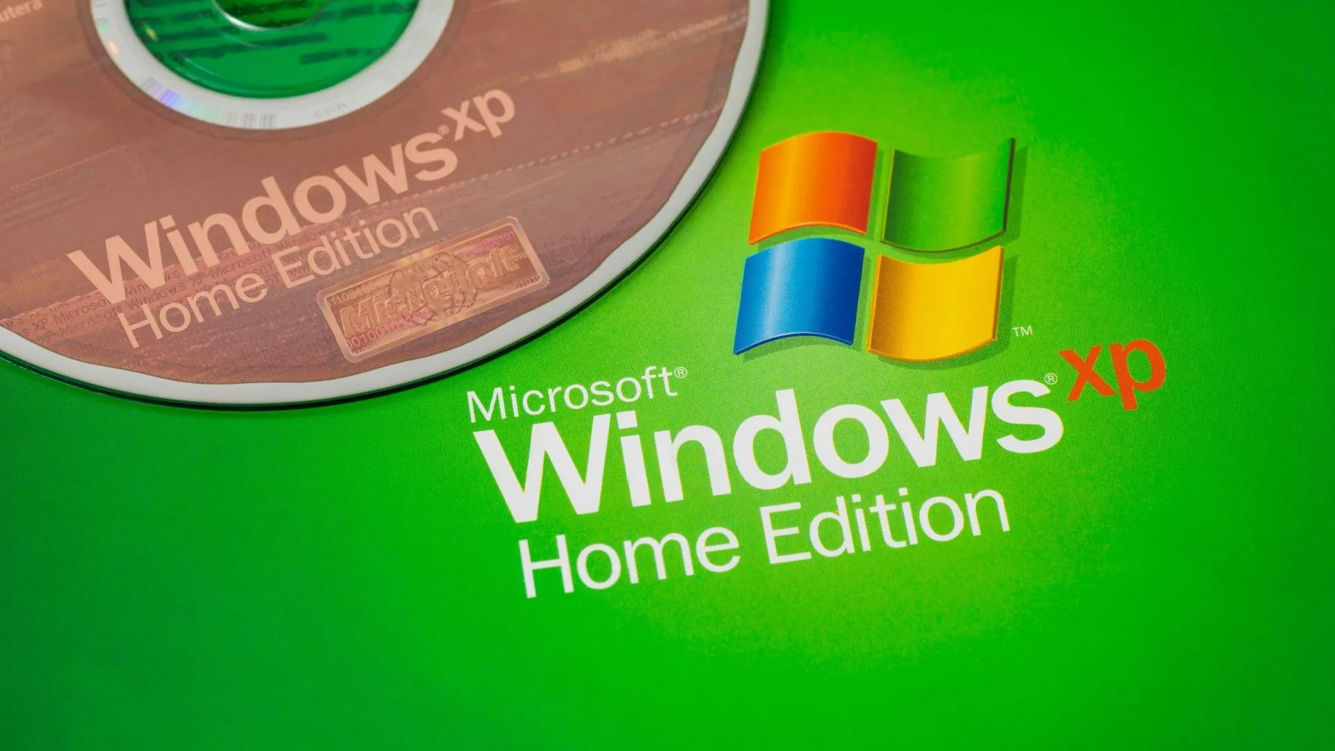 Đĩa cài Windows XP đặt cạnh logo Windows XP, biểu tượng của hệ điều hành cổ điển