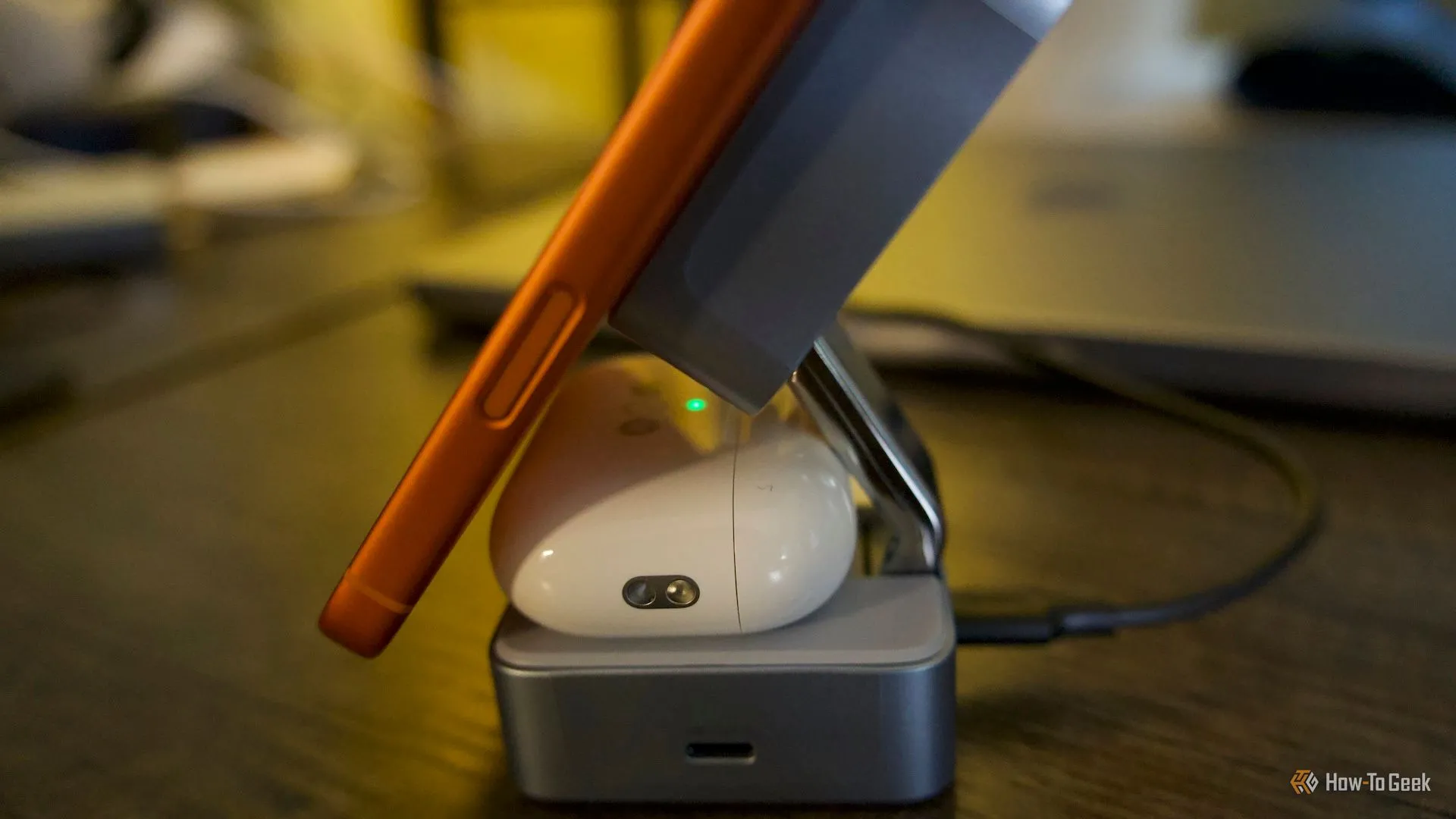 iPhone 17 Pro Max đặt trên đế sạc cùng hộp AirPods Pro 3, thể hiện khoảng cách chật chội và nguy cơ va chạm giữa hai thiết bị trên dock nhỏ gọn.