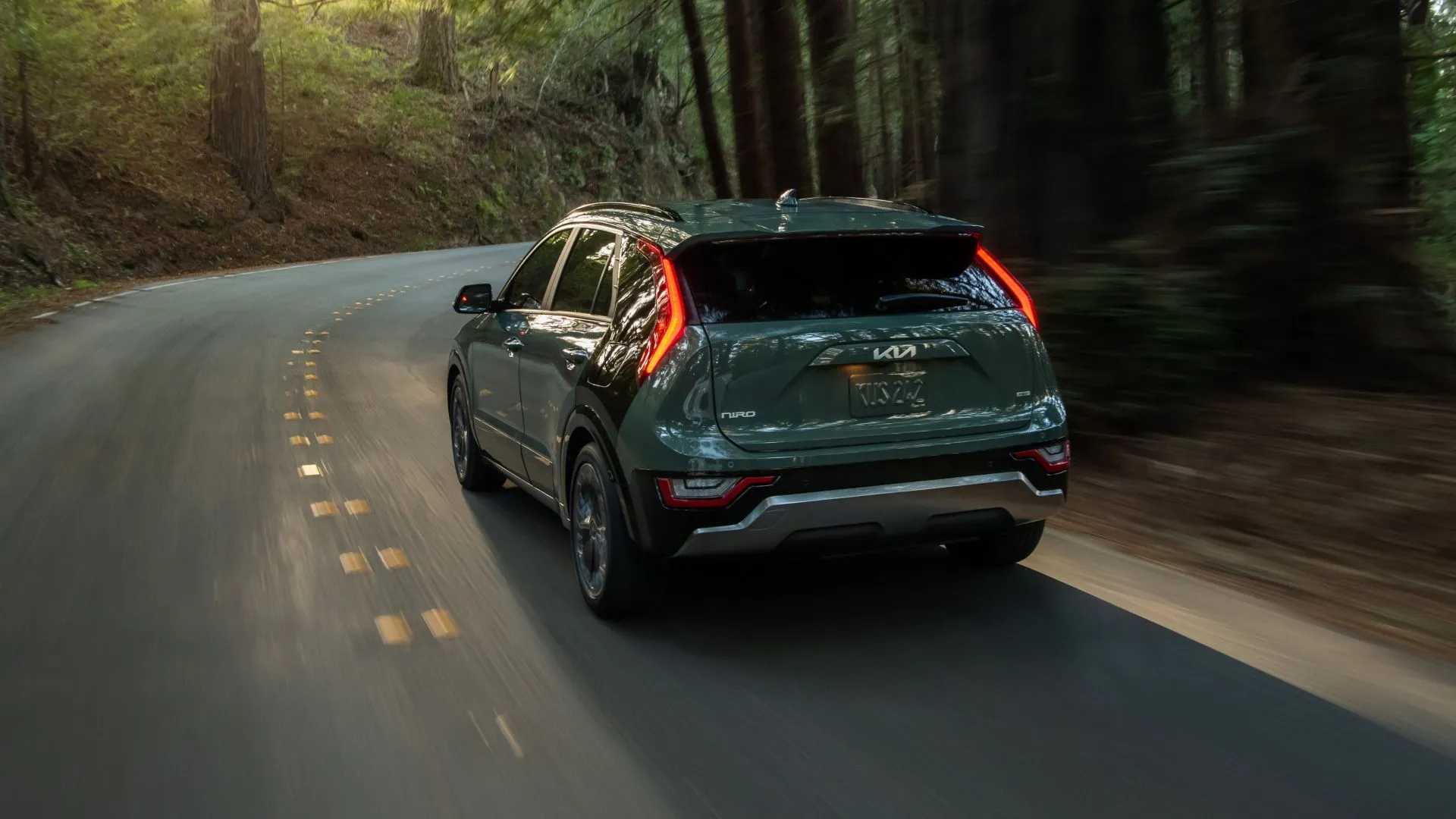 Kia Niro Hybrid 2025 góc nhìn sau 3/4 trên đường, minh họa hiệu suất nhiên liệu cao