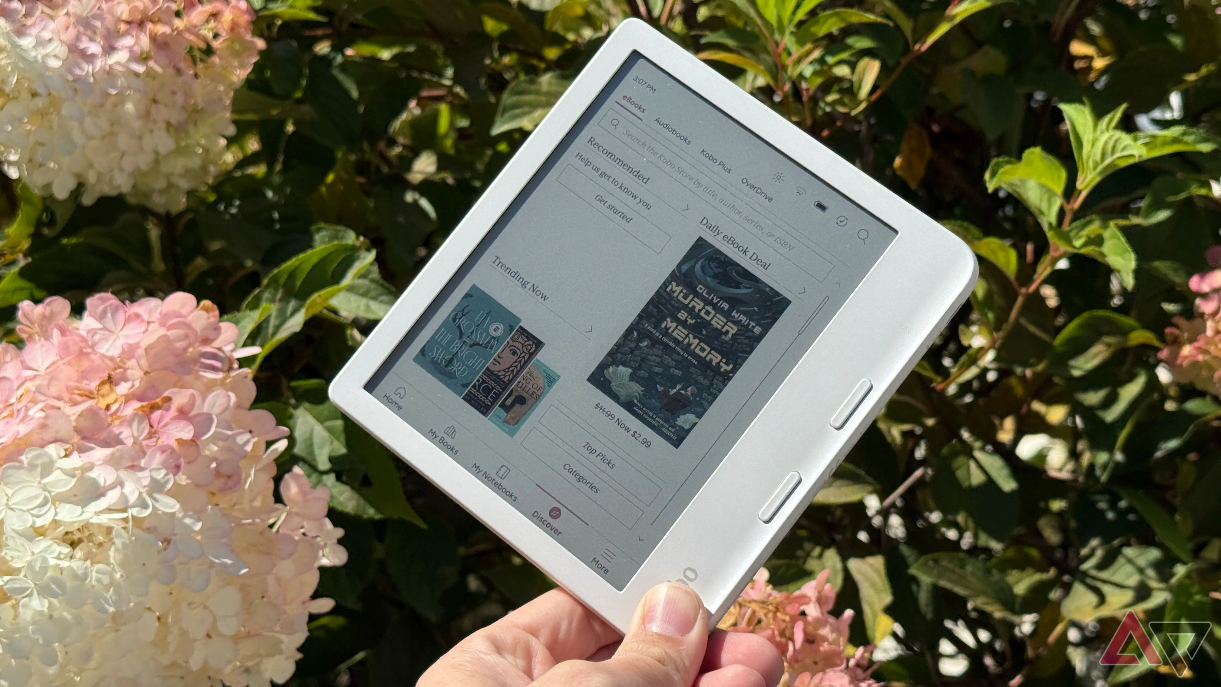 Kobo Libra Colour cầm trong tay giữa khung cảnh hoa lá tượng trưng thiết bị đọc sách thay thế điện thoại